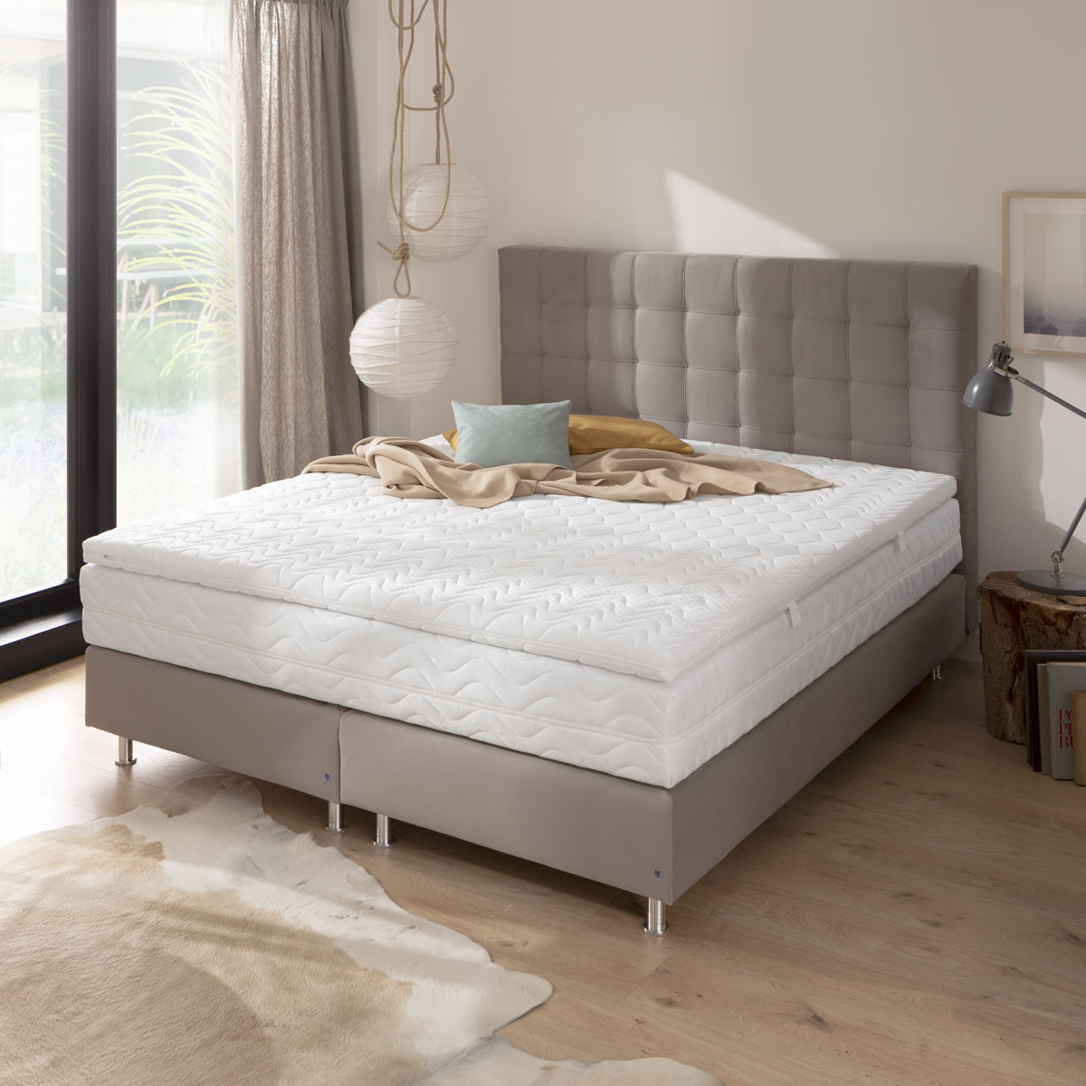 weißer Matratzentopper auf grauem Boxspringbett